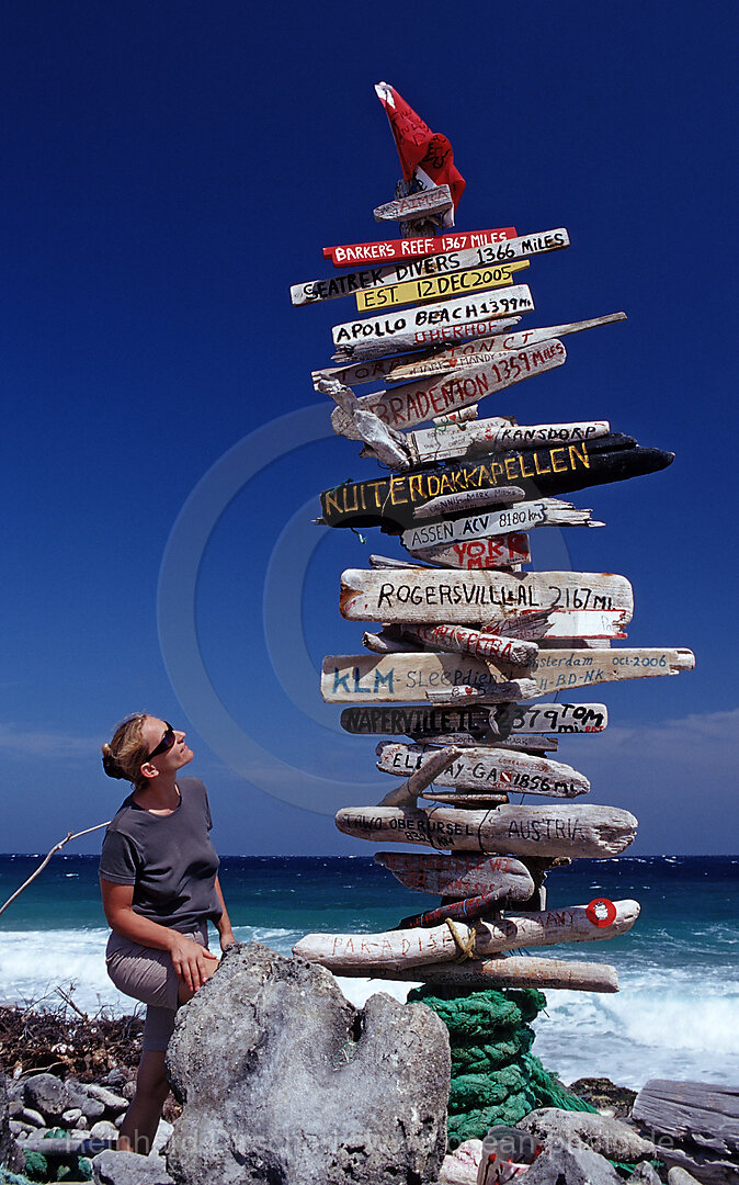 Tourist neben Entfernungsschild am Strand