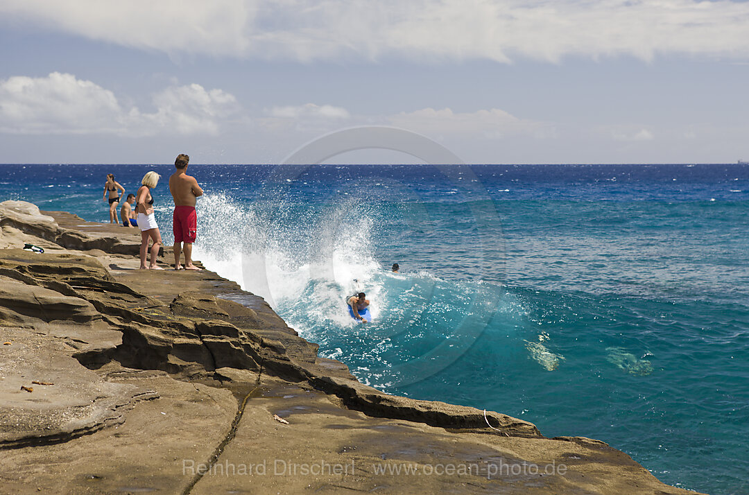 Touristen surfen in der Brandung den Chinawall Felsen am Kawaihoa Point