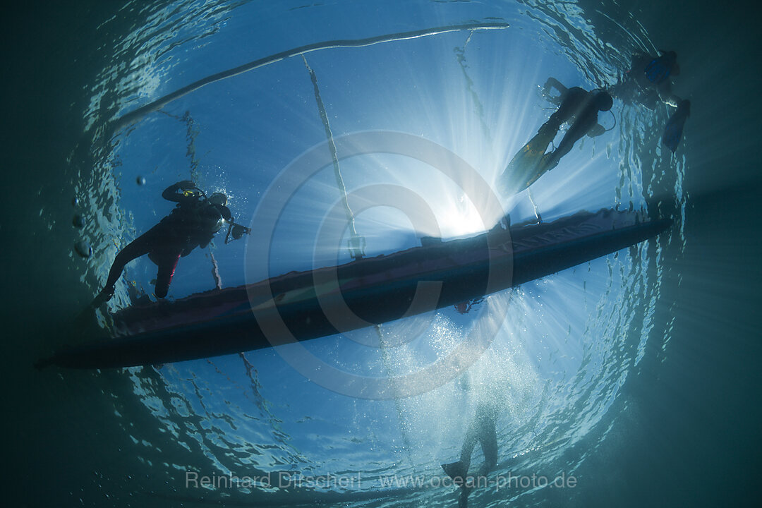 Scuba Divers underneath Outrigger Boat