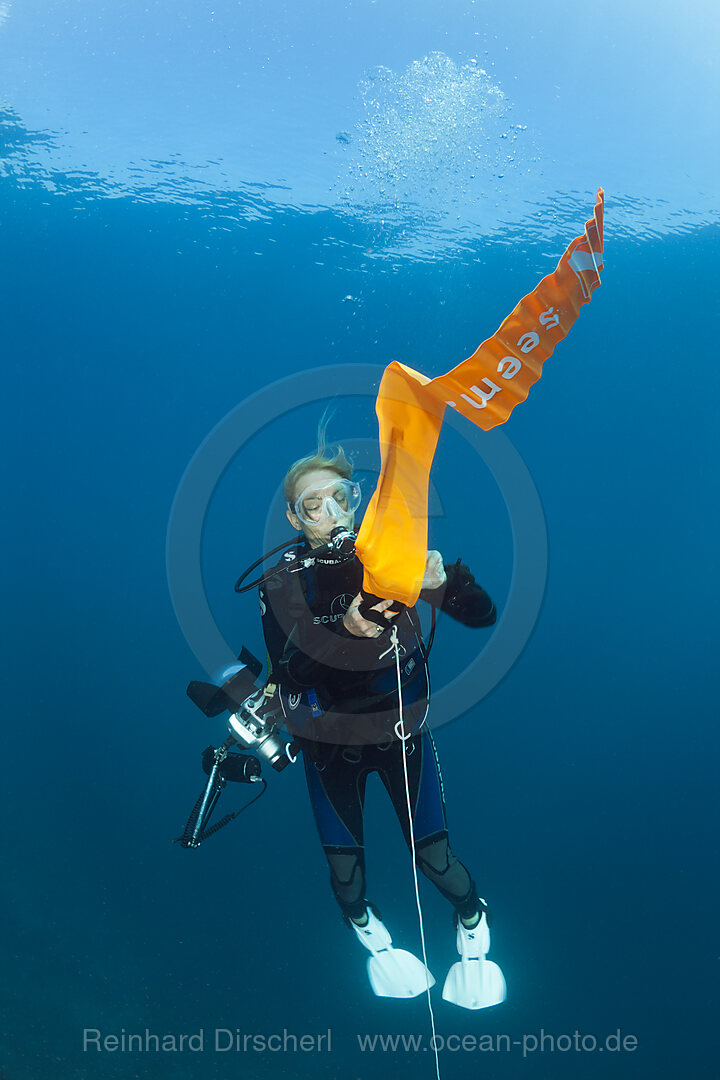 Scuba Diver inflates her Surface Marker Buoy