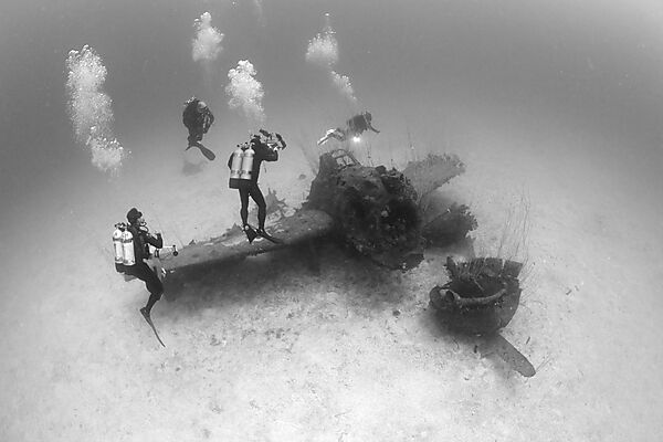 Taucher ueber Kampfflugzeug neben der USS Saratoga