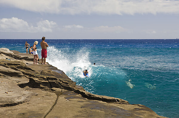 Touristen surfen in der Brandung den Chinawall Felsen am Kawaihoa Point