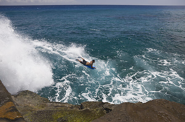 Touristen surfen in der Brandung den Chinawall Felsen am Kawaihoa Point