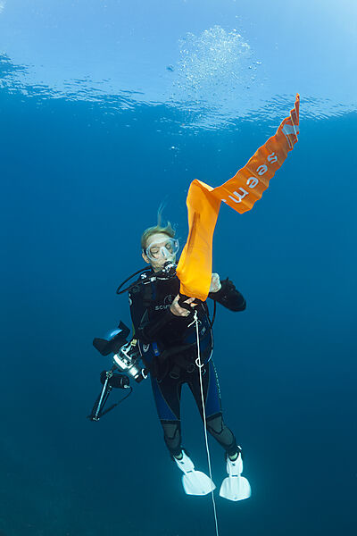 Scuba Diver inflates her Surface Marker Buoy